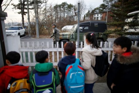 Children look at a soldier as they stand in a line to take a school bus at the Daesungdong Elementary School, a school inside the demilitarised zone separating the two Koreas, in Paju, South Korea, November 22, 2016.  REUTERS/Kim Hong-Ji 