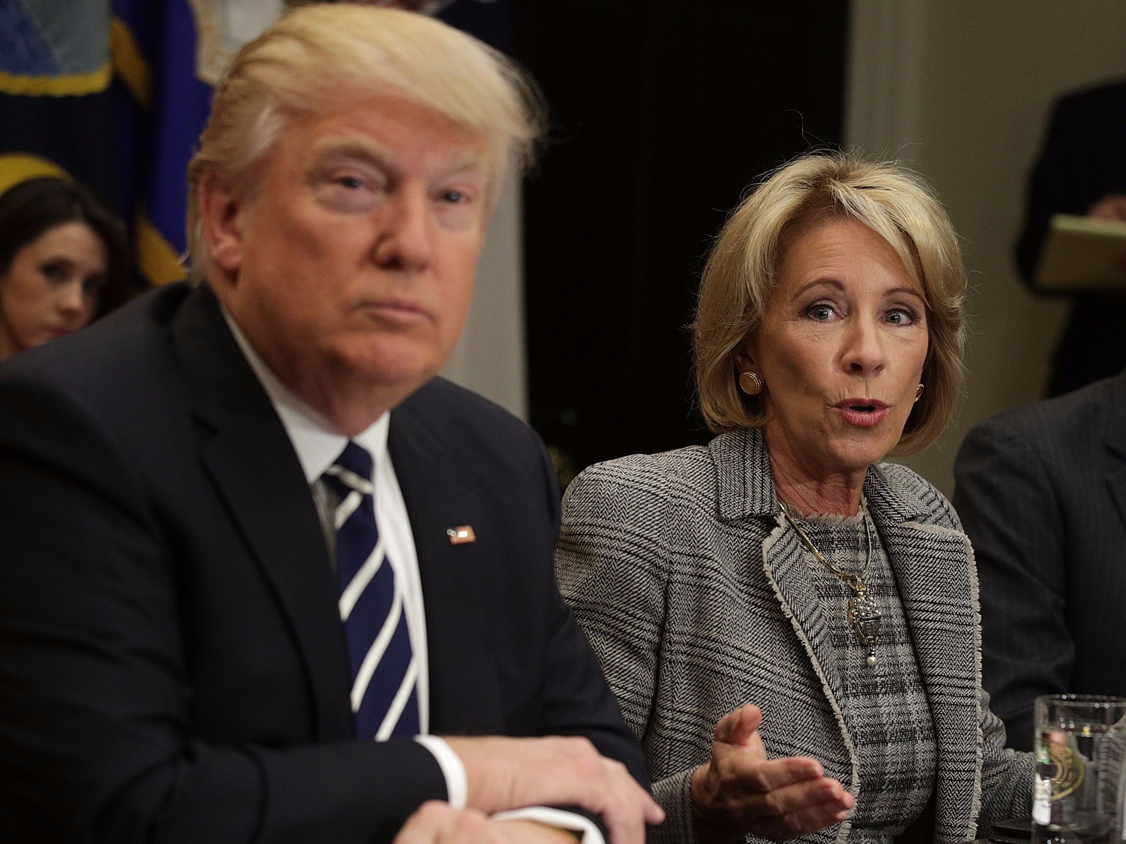 WASHINGTON, DC - FEBRUARY 14: U.S. Secretary of Education Betsy DeVos (C) speaks as President Donald Trump (L) and educator Kenneth Smith (R) listen during a parent-teacher conference listening session at the Roosevelt Room of the White House February 14, 2017 in Washington, DC. The White House held the session to discuss education.