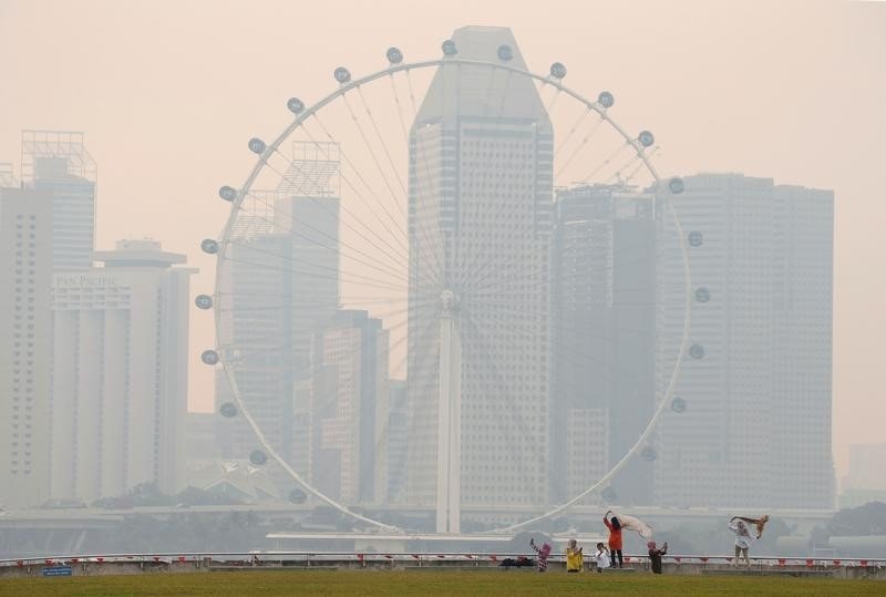People take photos near the Singapore Flyer observatory wheel shrouded by haze August 26, 2016. REUTERS/Edgar Su