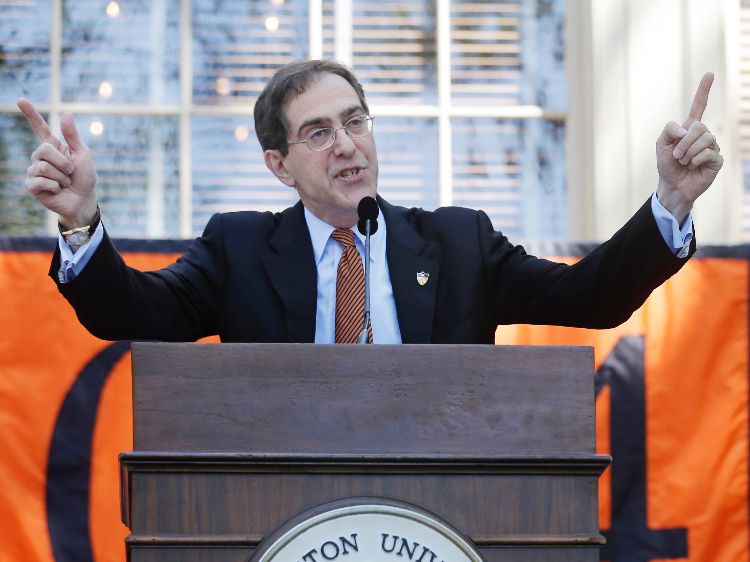 As a campus police officer holds a toy stuffed tiger, Princeton University President Christopher L. Eisgruber addresses the class of 2014 at Princeton University's Class Day, a mostly whimsical celebration the day before its commencement ceremony in Princeton, N.J., Monday, June 2, 2014. (AP Photo/Mel Evans)